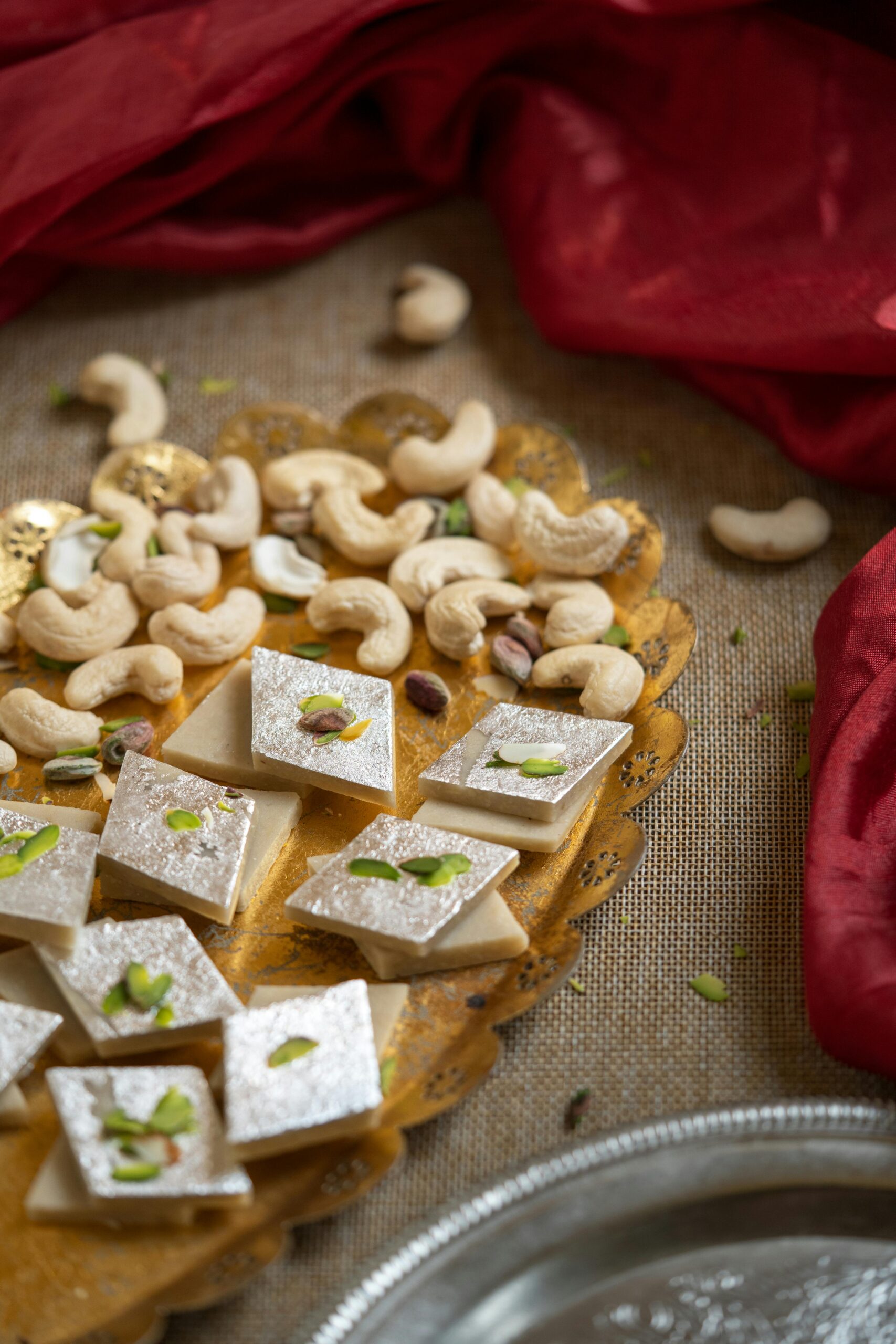 Traditional Indian sweets with cashews on golden plate, beautiful festive setup.