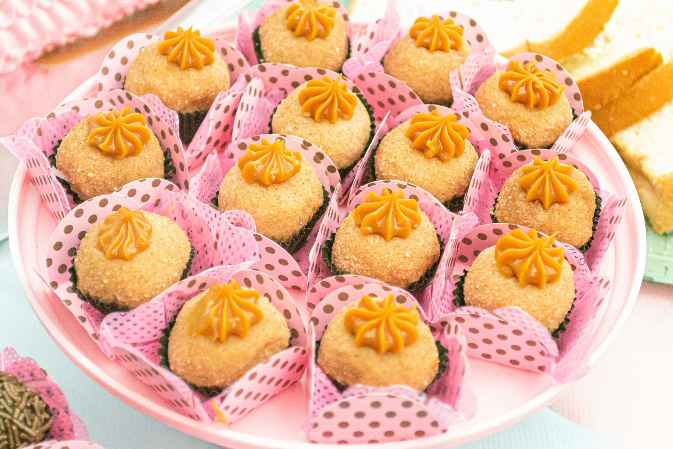 Assorted brigadeiros in pink polka-dot wrappers on a plate, ready to enjoy.
