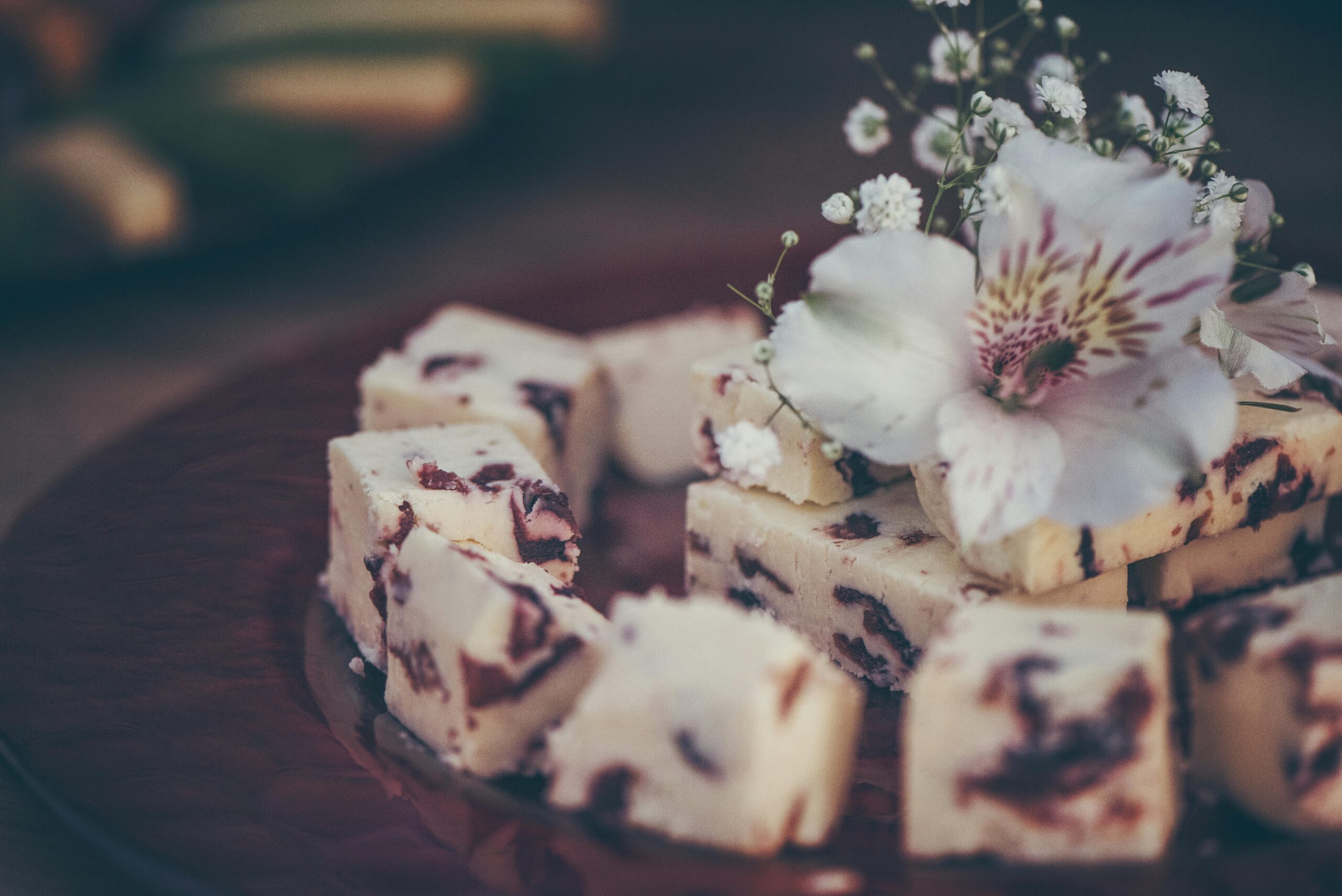 Close-up of a dessert plate featuring cubes of cheese with flower garnish, creating an elegant presentation.