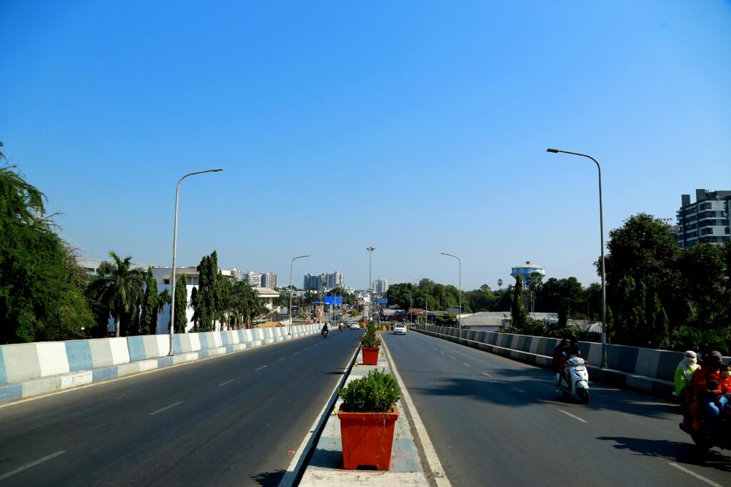 An urban highway in Surat, India, showcasing city infrastructure and traffic under a clear blue sky.